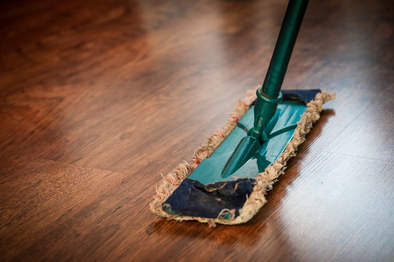Commercial Cleaning A detailed view of a mop cleaning a wooden floor, showing texture and pattern.