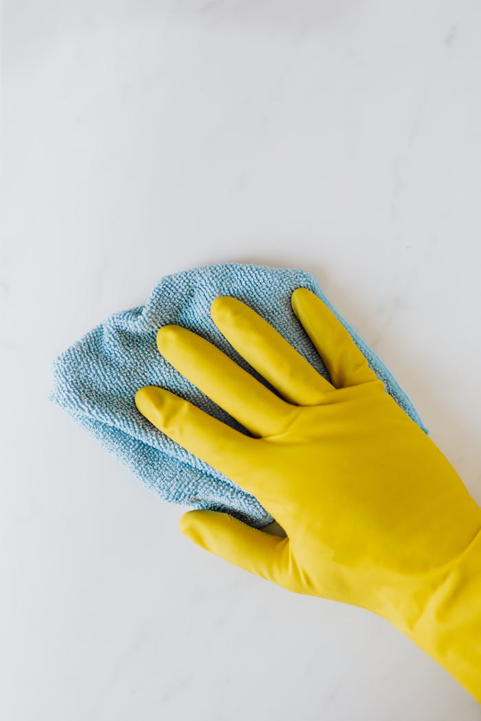 Commercial Cleaning Yellow gloved hand wiping surface with blue cloth, concept of cleaning and hygiene.